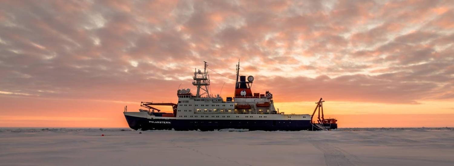 The Polarstern ship parked in Arctic ice at sunset.